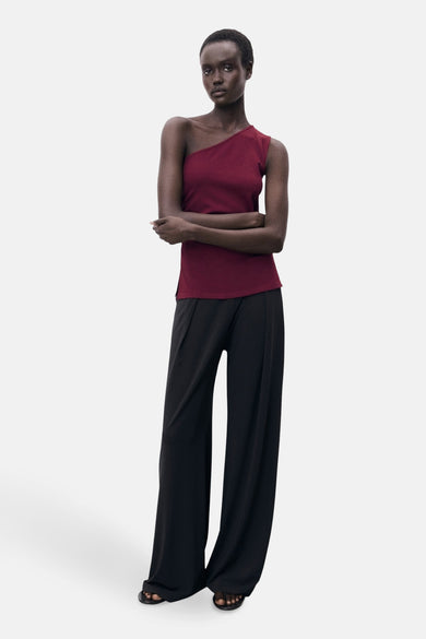 Bordeaux top sans manches de MANGO, portée avec un pantalon noir large et des sandales.