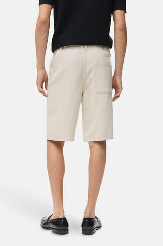 Jean court en écru de MANGO, avec une poche à l'arrière et porté avec des loafers noirs.