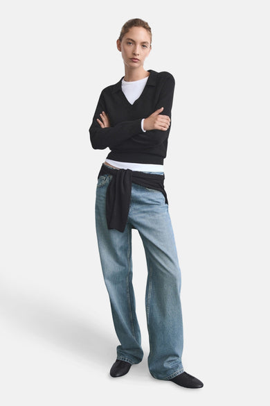 Jean bleu droit "MIAMI" de MANGO, avec une chemise noire déboutonnée à la taille.