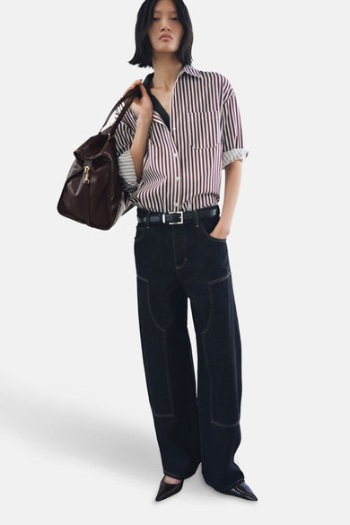 Chemise multicolore à manches longues de MANGO, avec des rayures verticales et un sac en cuir marron sur l'épaule.