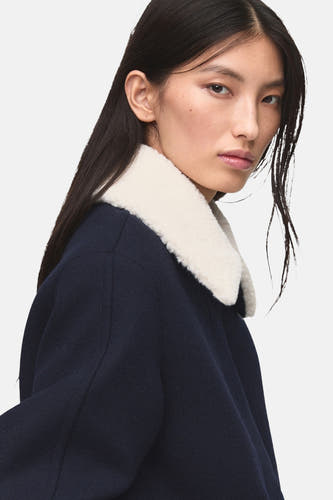 Manteau court bleu de MANGO avec un col blanc en fourrure synthétique.