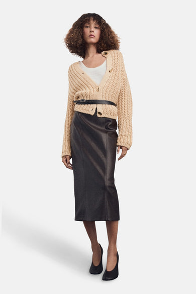 Beige gilet van MANGO, gestyled met een witte top, zwarte leren rok met riem en zwarte pumps.
