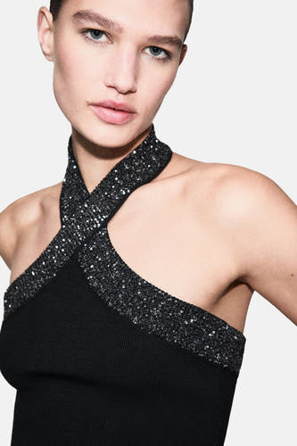 Blouse sans manches noire de MANGO, avec des bandes glitterées croisées et une texture côtelée.