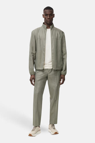 Veste courte verte de MANGO portée sur un t-shirt crème et un pantalon coordonné.