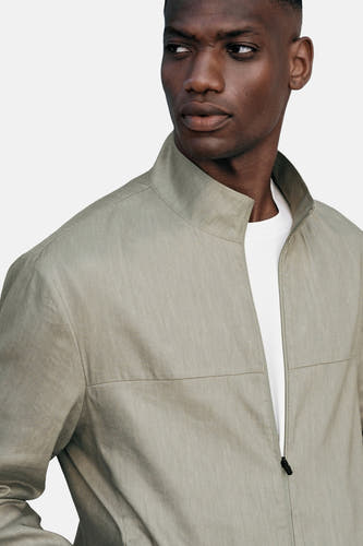 Manteau vert, court de MANGO avec un col haut et une T-shirt blanche en dessous.