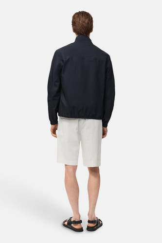 Courte veste bleue de MANGO, vue de derrière, portée avec des shorts rayés et des sandales.