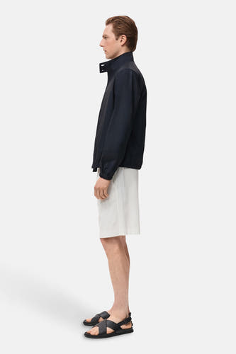 Veste courte bleue de MANGO portée avec des shorts rayés et des sandales en cuir, vue latérale.