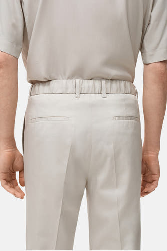 Jean écru de MANGO, avec une ceinture élastique et des poches passepoilées à l'arrière, vu de derrière.