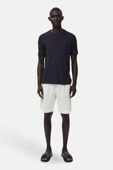 T-shirt noir à manches courtes de MANGO, porté avec des shorts rayés et des sandales noires.