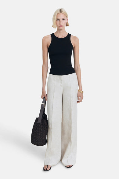 T-shirt noir de MANGO, porté avec un short en lin blanc et large, une sacoche noire et un bracelet doré.