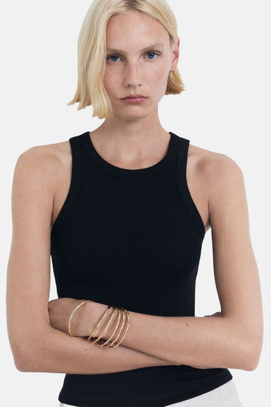 T-shirt noir de MANGO, avec des bras croisés portant des bracelets en or, contre un fond blanc.