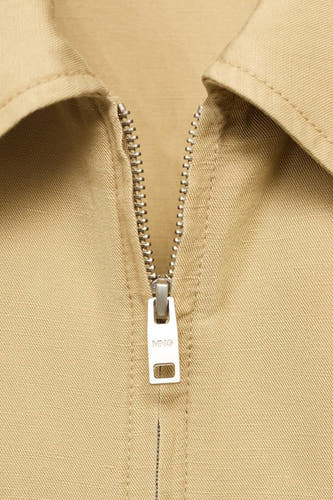 Manteau court beige de MANGO, avec fermeture éclair et collet argentés.