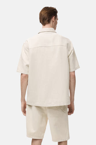 Chemise de jeans écru de MANGO, vue de dos avec des manches courtes et une coupe décontractée.
