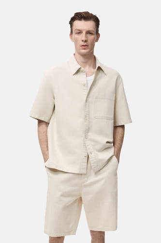 Jean brut MANGO, avec des manches courtes et une poche poitrine, porté port un T-shirt blanc.