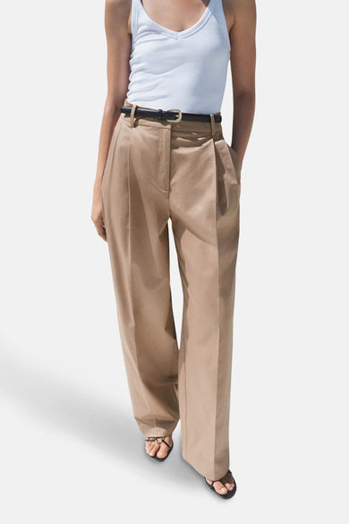 Pantalon beige de MANGO, avec cece et des etes larges, associé à un chemisier blanc et des sandales.