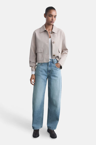 Jean en denim bleu clair de MANGO, avec des jambes larges et porté avec un blouson beige.
