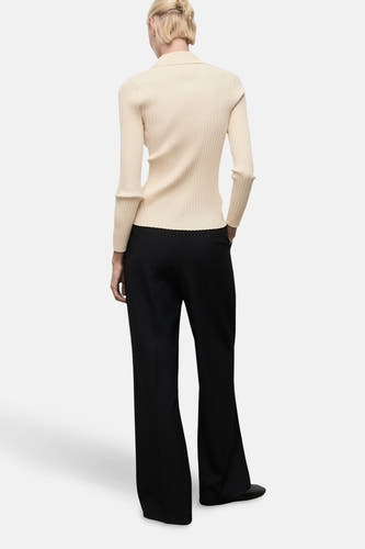 Cardigan jaune de MANGO, avec des manches longues, une texture côtelée et porté avec un pantalon noir.