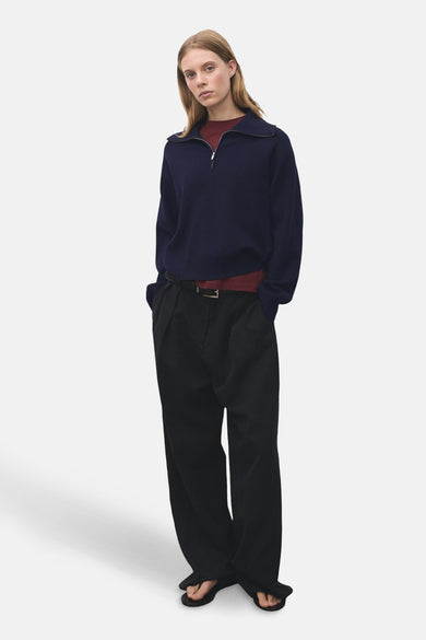 T-shirt bleu avec col montant de MANGO, à longues manches, porté sur un t-shirt bordeaux et un pantalon noir.