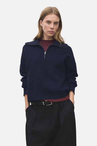 T-shirt bleu à col montant de MANGO, avec une fermeture éclair argentée et associé à un pantalon noir à ce.