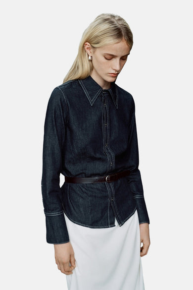 Chemise en denim bleu marine à manches longues de MANGO, finie avec des surures blanches et une fine ceinture.