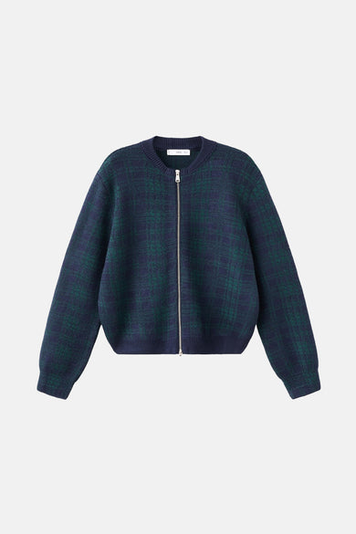 Gilet multicolore de MANGO, porté avec des jeans foncés, un manteau à fermeture éclair et des lunettes de soleil.