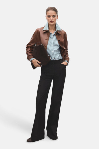 Chemise rayée verte à longues manches de MANGO, portée avec une veste en cuir brune et un pantalon noir.