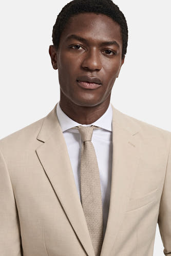 Blazer beige de MANGO, avec une chemise blanche et une cravate structurée coordonnée.