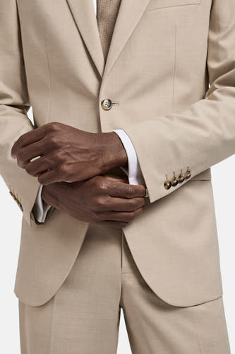 Blazer beige de MANGO, avec des manches longues et des boutons dorés, en tant qu'élément d'un ensemble deux pièces.