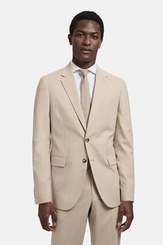 Blazer beige de MANGO, porté avec une chemise blanche et une cravate coordonnée.