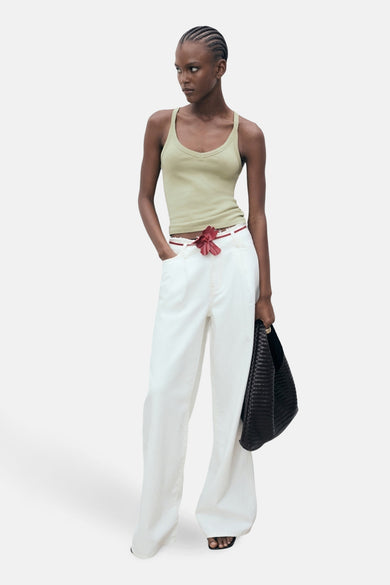 Tête de avec avec des bandes spaghetti MANGO, combinéeée un pantalon blanc et une sac noir.
