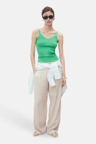 T-shirt vert de MANGO, porté avec un chemisier blanc noué à la taille et un pantalon beige.