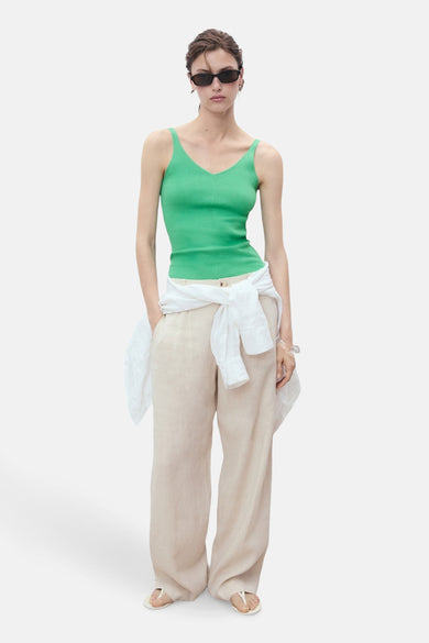 T-shirt vert de MANGO, porté avec un chemisier blanc noué à la taille et un pantalon beige.