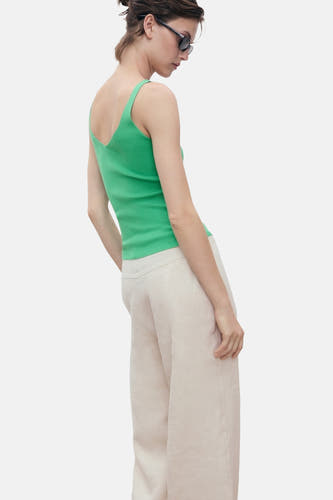 Maillot vert de MANGO porté avec un short en lin beige et des lunettes de soleil, vue arrière.