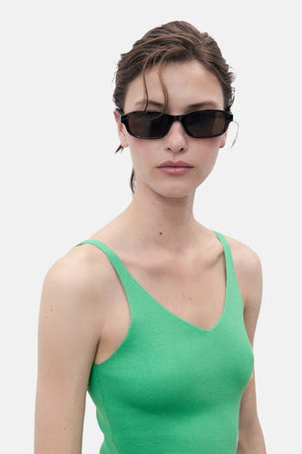 T-shirt vert de MANGO, porté avec un chapeau de soleil, contre un fond blanc.
