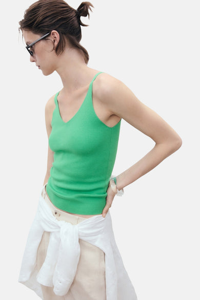 T-shirt vert de MANGO, avec un col V et une texture rayée, associé à une blouse blanche nouée à la taille.