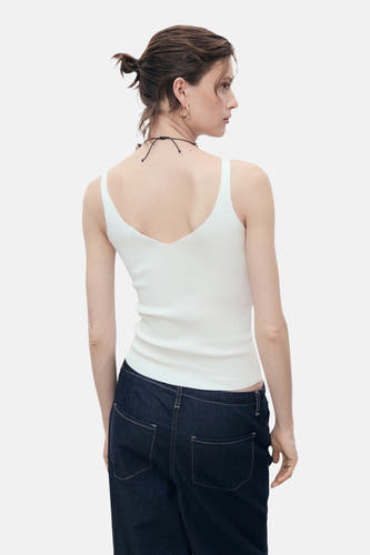 T-shirt blanc de MANGO, avec col V à l'arrière, associé à des jeans foncés.