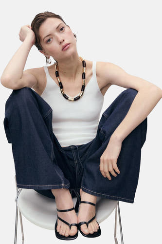 T-shirt blanc de MANGO porté avec des jeans larges et des sandales noires dans un cadre de vie.