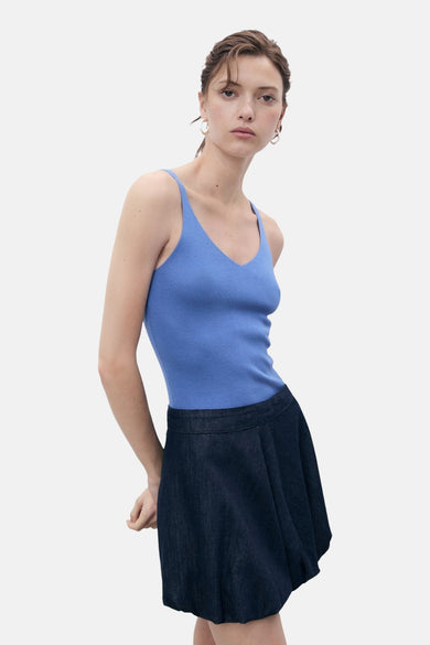 Maillot bleu de MANGO, avec des fines bretelles et une texture à côtes, porté avec une jupe bleue marine.