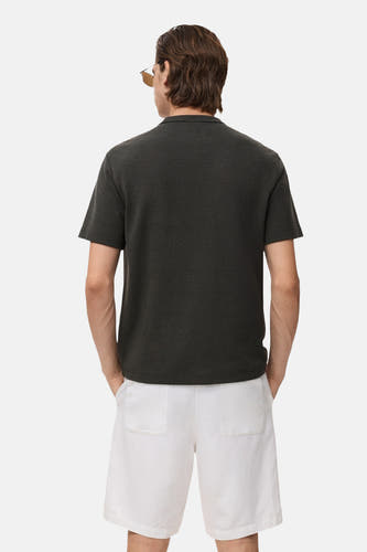 T-shirt noir à manches courtes de MANGO, vu de derrière, associé à un short blanc.