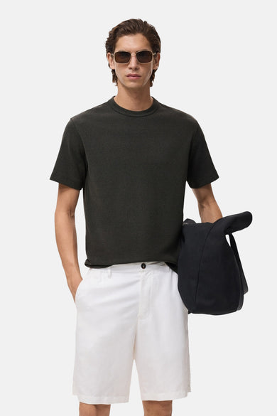 T-shirt noir à manches courtes de MANGO, porté avec des shorts blancs et un chapeau de soleil.