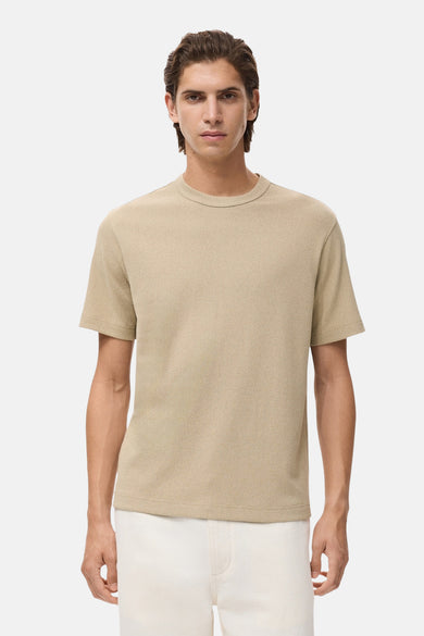 T-shirt beige à manches courtes de MANGO, tissu uni, porté avec un short blanc.