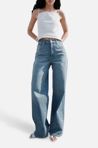 Jean décontracté en denim bleu moyen de MANGO, avec un haut blanc et des sandales.