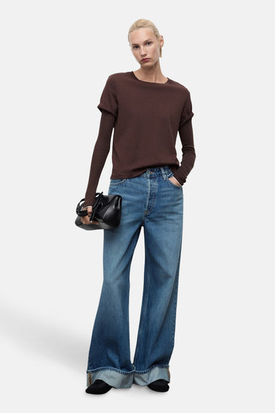Middenblauwe wide jeans van MANGO, gecombineerd met een bruine top en zwarte handtas.
