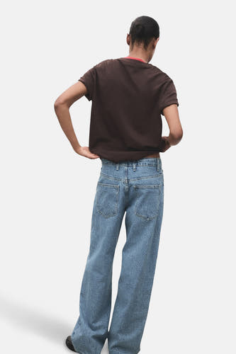 Jean bleu droit de MANGO, avec un motif texturé, vu de derrière, associé à une chemise brune.