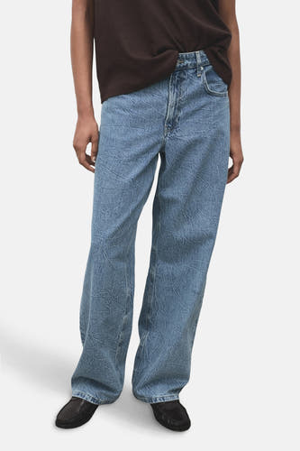 Jean droit en denim bleu de MANGO, avec une texture froissée et un ajustement décontracté.