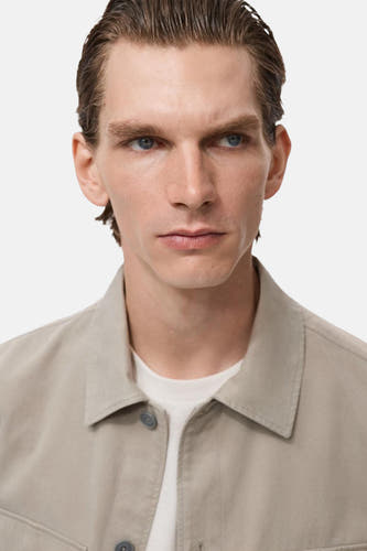Chemise beige (manches longues) de MANGO, avec un col classique et une fermeture à boutons visible.