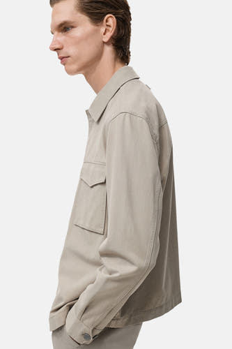 Chemise beige à manches longues de MANGO, avec poche et fermeture à boutons, en vue latérale.