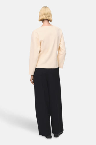Gilet écru de MANGO, vu de l'rièrerière combiné avec une avec noir pantalon large.