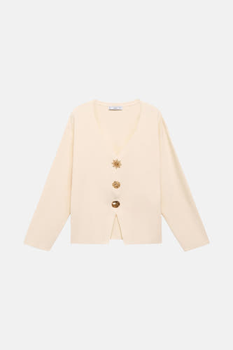 Gilet écru de MANGO avec col V, longues manches et boutons dorés décoratifs.