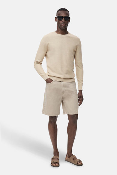 Pull beige à col rond de MANGO, porté avec un short et des sandales.